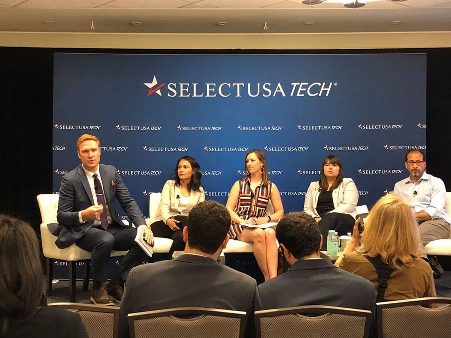 Panel on stage in front of a SelectUSA Tech backdrop, seen from the audience