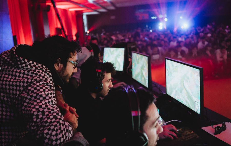 Tunisia’s esports players at their stations during a live tournament, with the team manager leaning in to watch